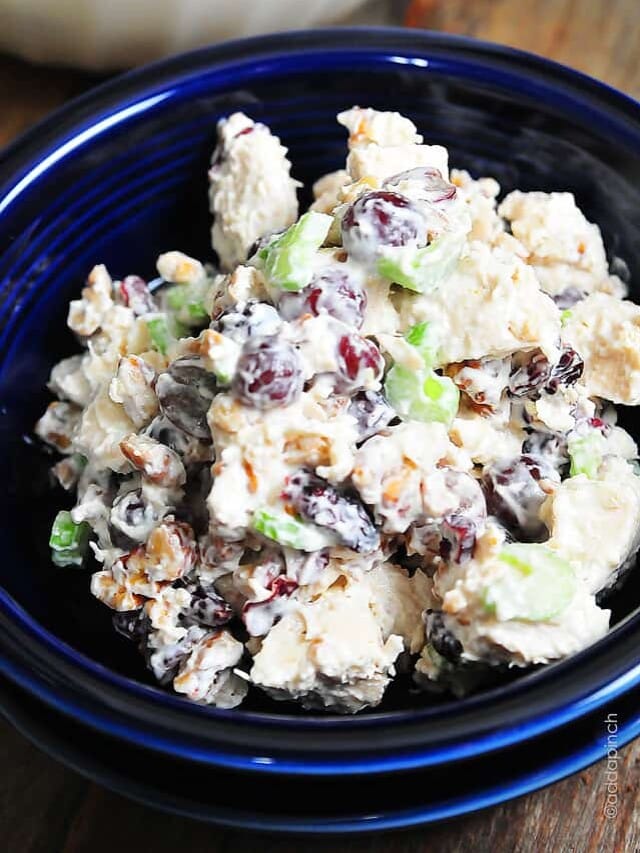 Photograph of chicken salad in a blue bowl on a dark counter.