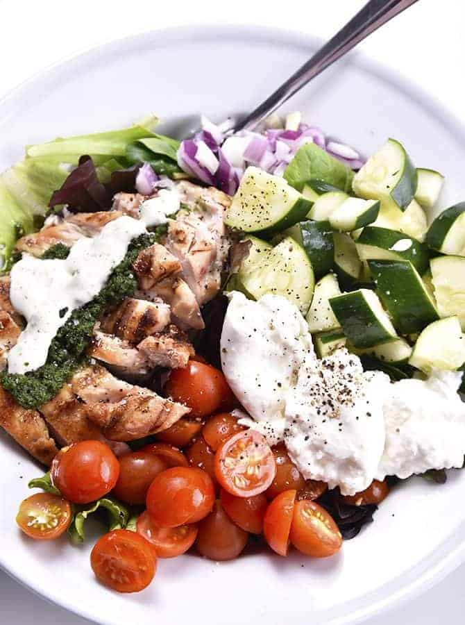 Grilled Chicken Salad with Pesto Ranch Dressing Recipe makes a delicious salad with cucumbers, tomatoes, onion, mozzarella topped with grilled chicken and a pesto ranch dressing! // addapinch.com