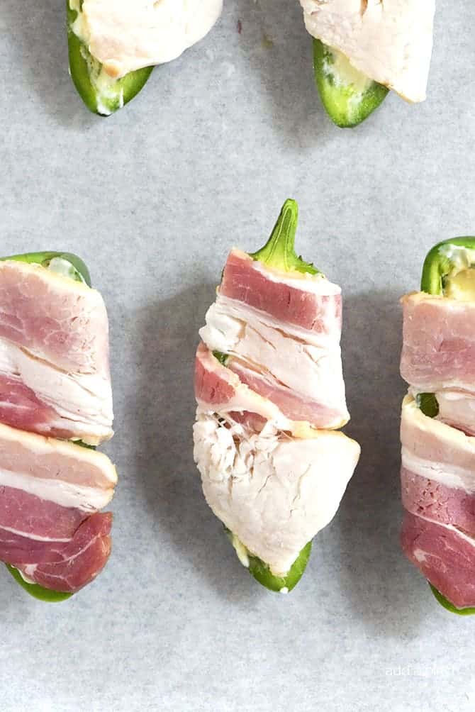 Pineapple Jalapeno Popper Recipe - Sweet and spicy, these jalapeno poppers are made with a pineapple cream cheese spread, wrapped with bacon and baked to perfection! // addapinch.com