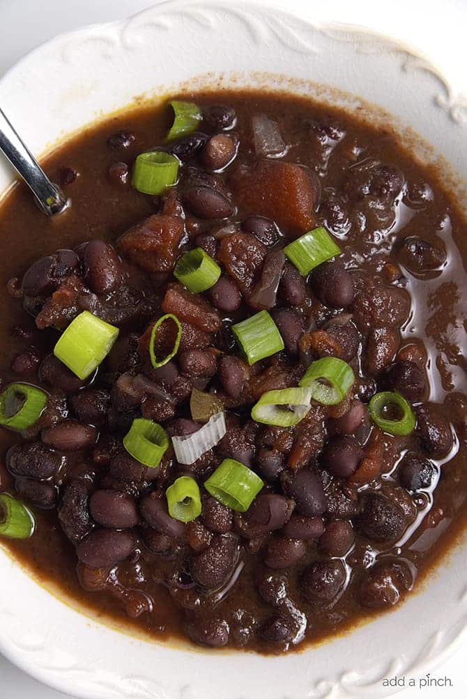 White bowl filled with black bean soup topped with green onion // addapinch.com