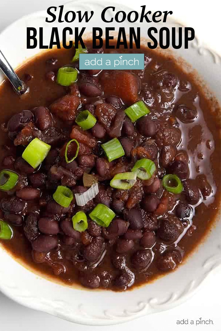 Slow Cooker Black Bean Soup topped with green onion in white bowl - with text - addapinch.com