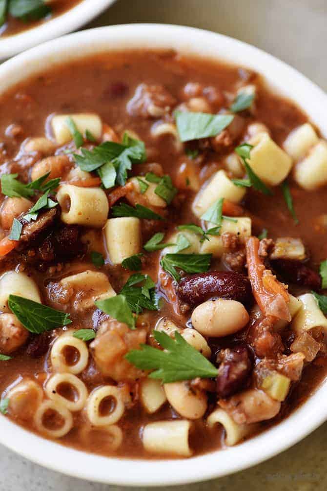 Pasta Fagioli with dark beans, pasta and herbs in a white serving bowl // addapinch.com