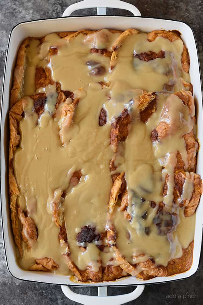 Pumpkin Bread Pudding with maple cream sauce in white dish. 