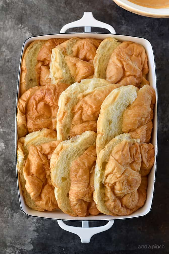 Sliced croissants in a white baking dish. 