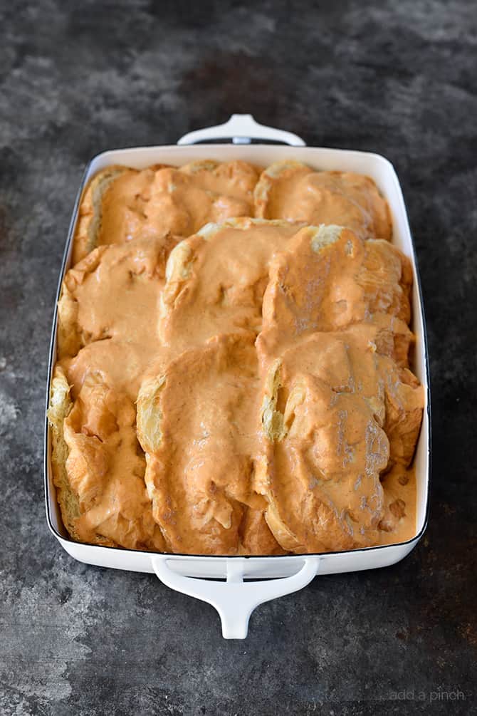 White baking dish with croissants covered in pumpkin custard. 