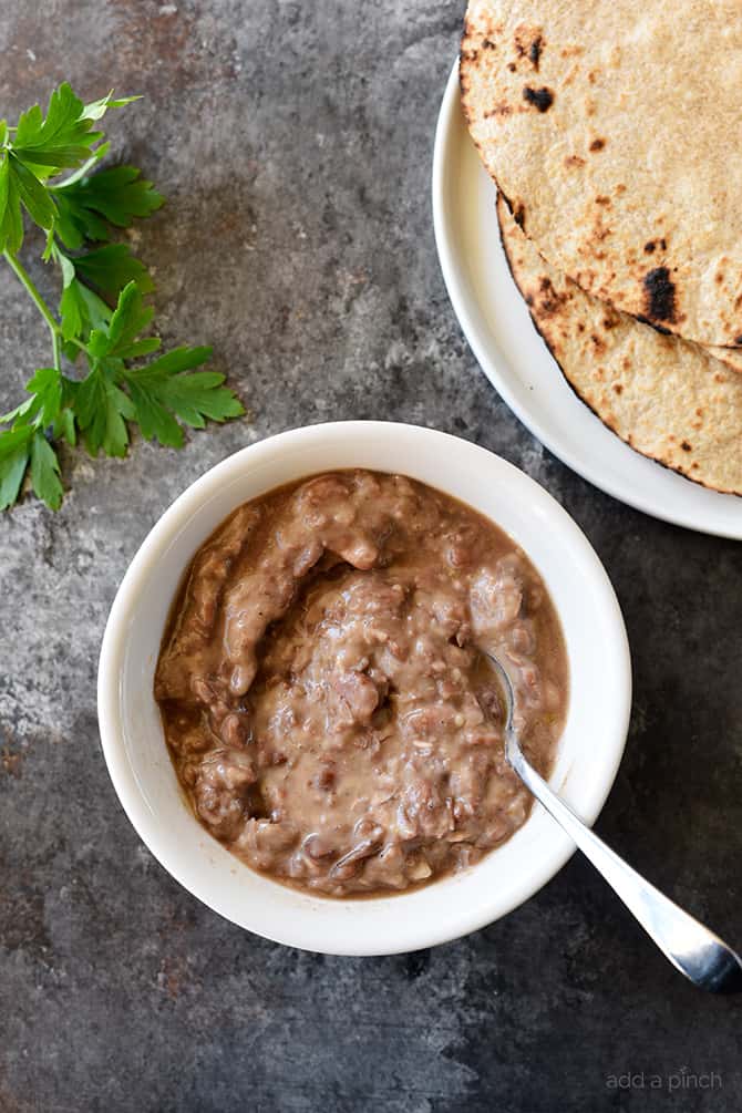 Refried Beans Recipe - This quick and easy refried beans recipe made with pinto beans, onion, and spices makes a delicious side dish for so many meals! // addapinch.com