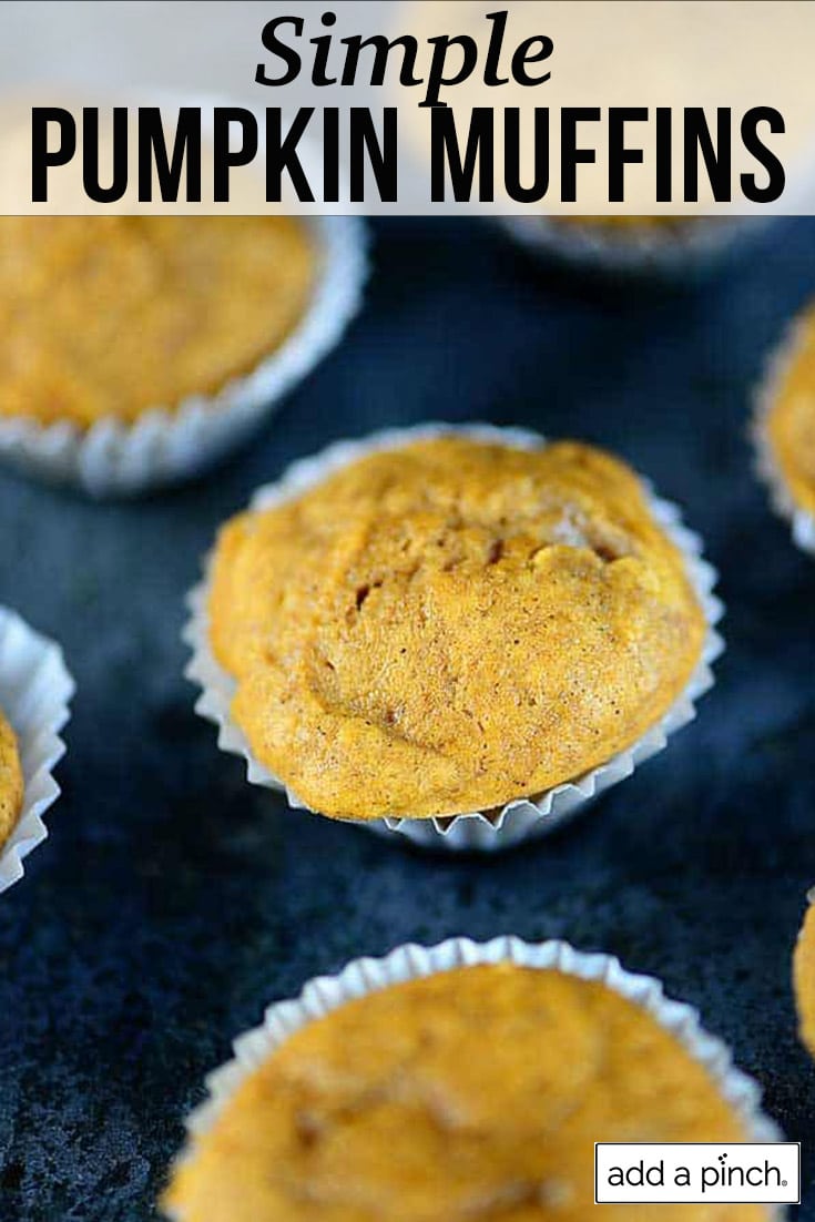 Pumpkin muffins in paper muffin cups on a dark baking sheet - with text - addapinch.com