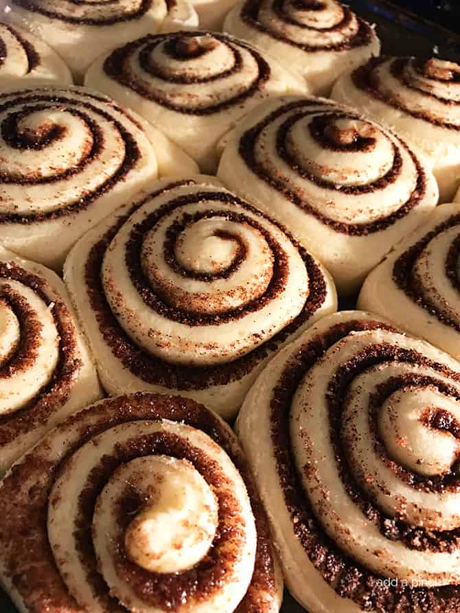 Baking sheet full of rolled cinnamon rolls showing cinnamon mixture in the swirls of dough // addapinch.com