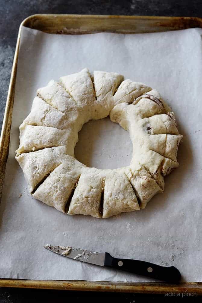 Dough for Cinnamon Roll Biscuits shaped into wreath on a baking sheet with parchment - addapinch.com