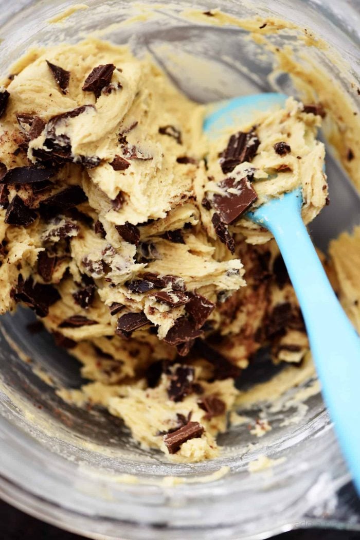 Closeup photograph of chocolate chip cookie dough in a glass mixing bowl. // addapinch.com