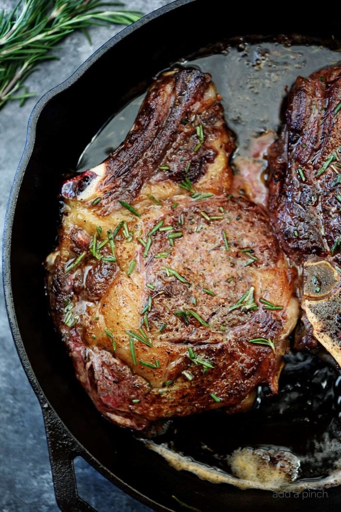 Skillet Rib Eye Steaks basted in butter in an iron skillet. Topped with rosemary and seasoning // addapinch.com