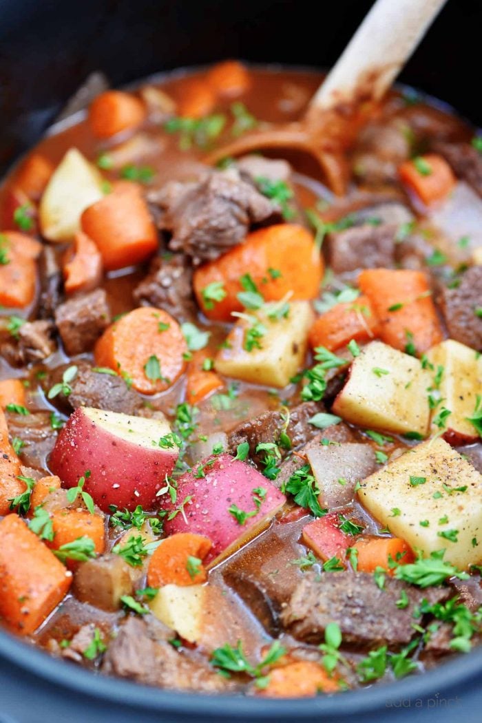 Wooden spoon stirring beef bourguignon in a slow cooker // addapinch.com