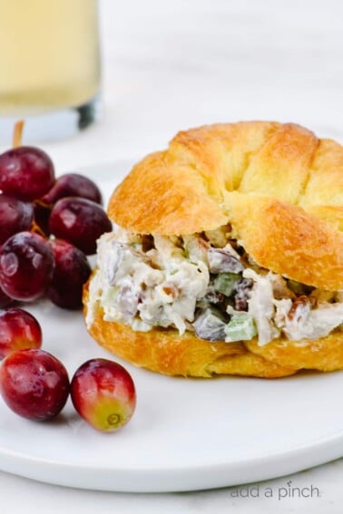 Chicken Salad on a croissant surrounded by red grapes.