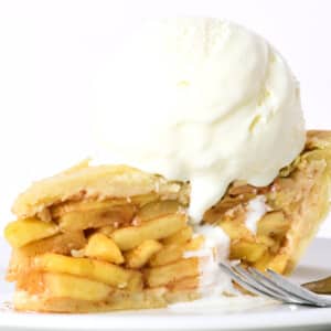 Slice of homemade apple pie with a scoop of vanilla ice cream on top.