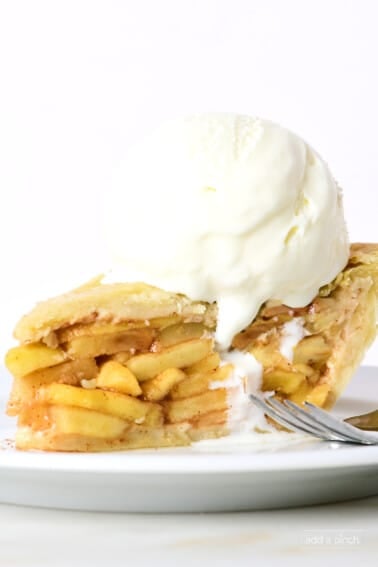 Slice of homemade apple pie with a scoop of vanilla ice cream on top.