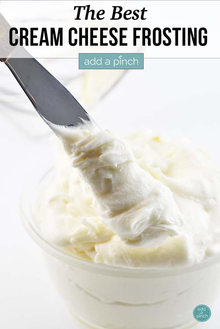 Fluffy Cream Cheese Frosting in a clear bowl with spatula - with text - addapinch.com
