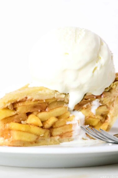 Slice of homemade apple pie with a scoop of vanilla ice cream on top.