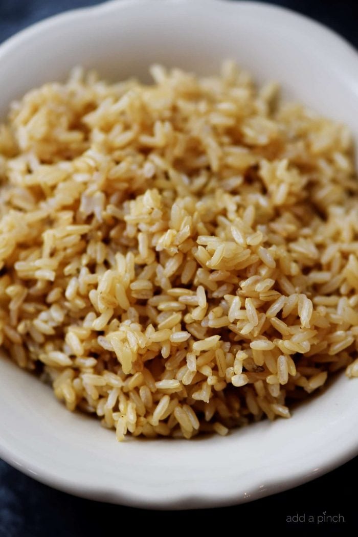 Cooked brown rice in a white serving bowl.