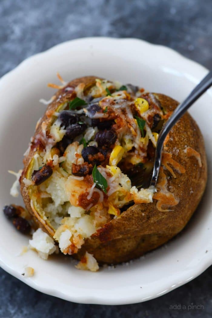 Air Fryer Enchilada Stuffed Baked Potatoes Recipe - This quick and easy recipe combines a perfect baked potato filled with black beans, enchilada sauce, and more! // addapinch.com