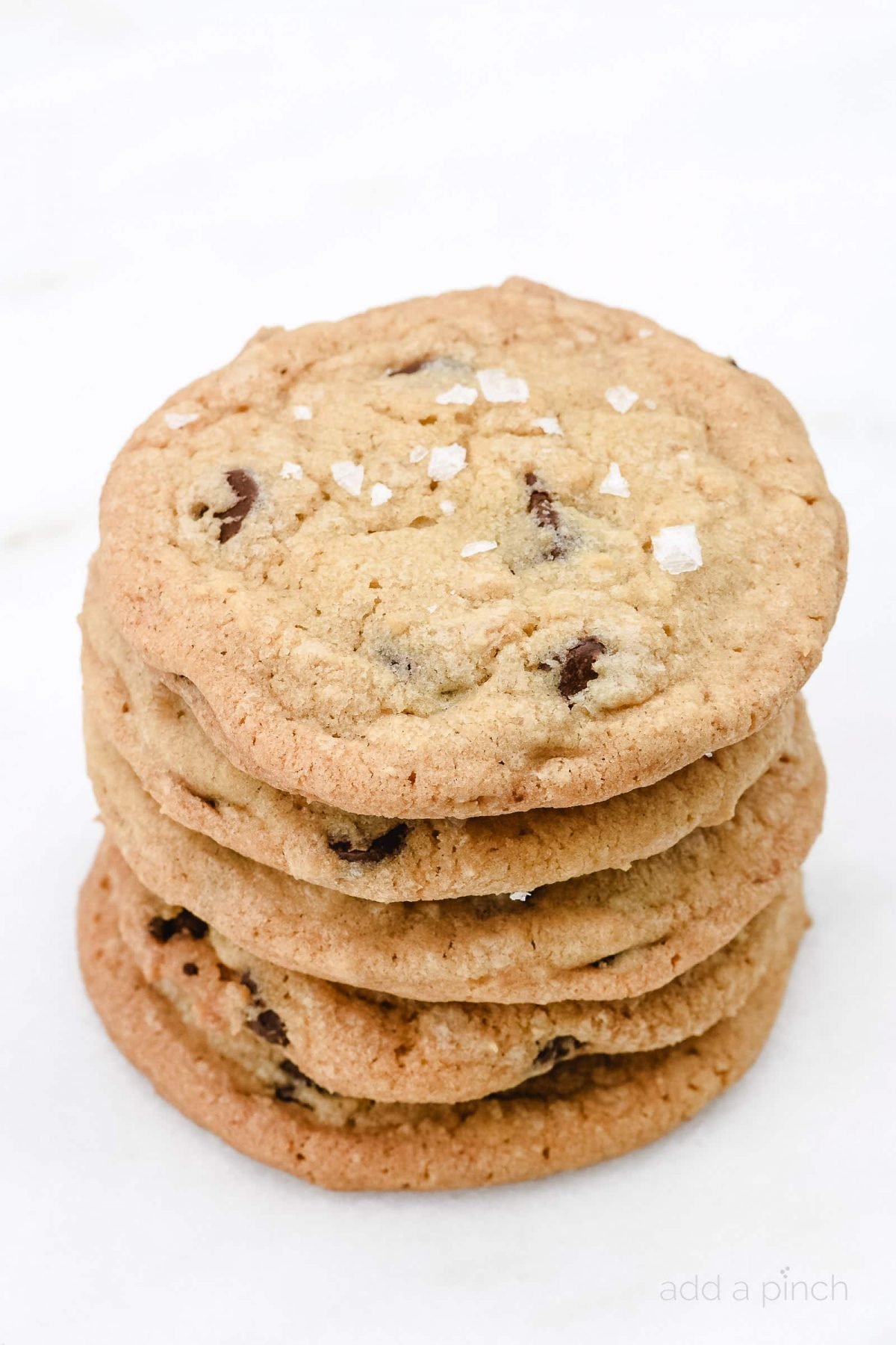 Stack of several chocoalte chip cookies on a white surface. 