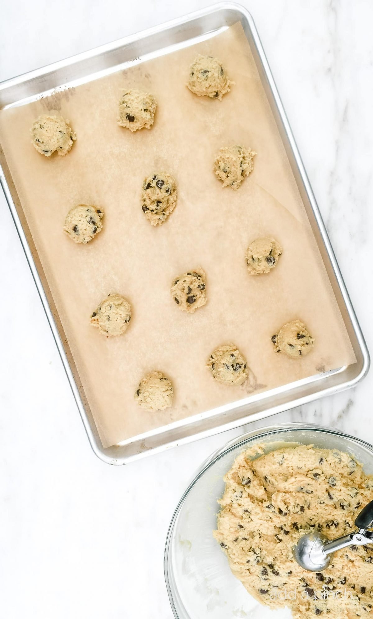 Chocolate chip cookie dough in balls on parchment lined baking sheet ready to bake.