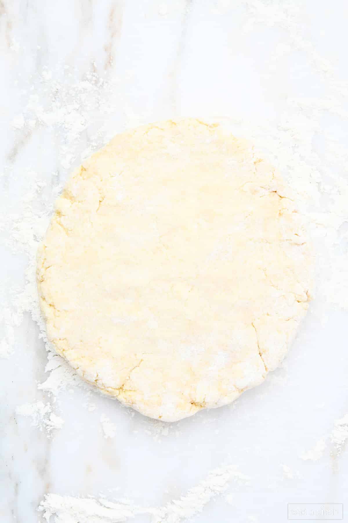 Easy scones recipe dough patted into a disc on a lightly floured marble surface.