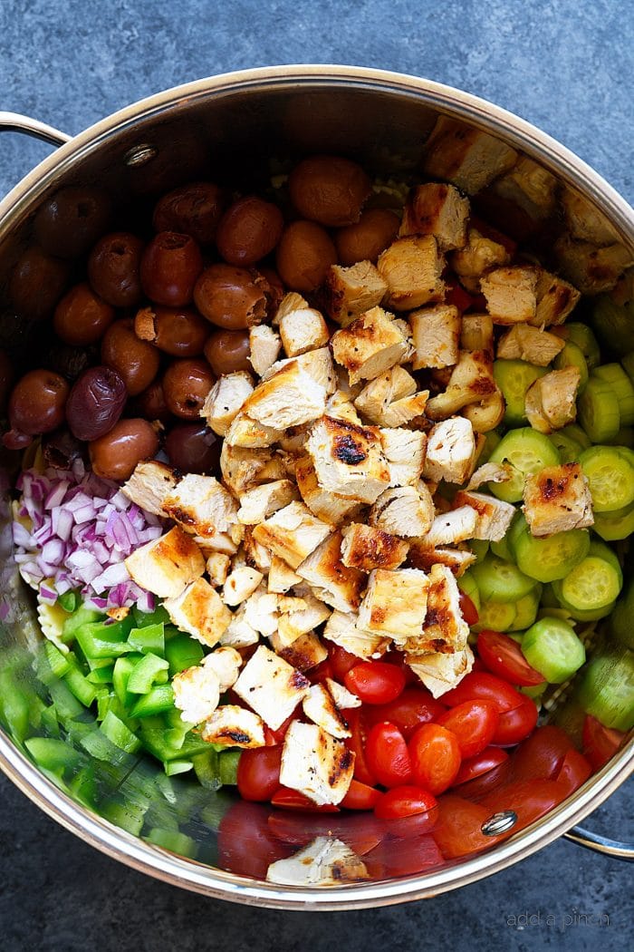 Greek Chicken Pasta Salad ingredients in large stainless bowl