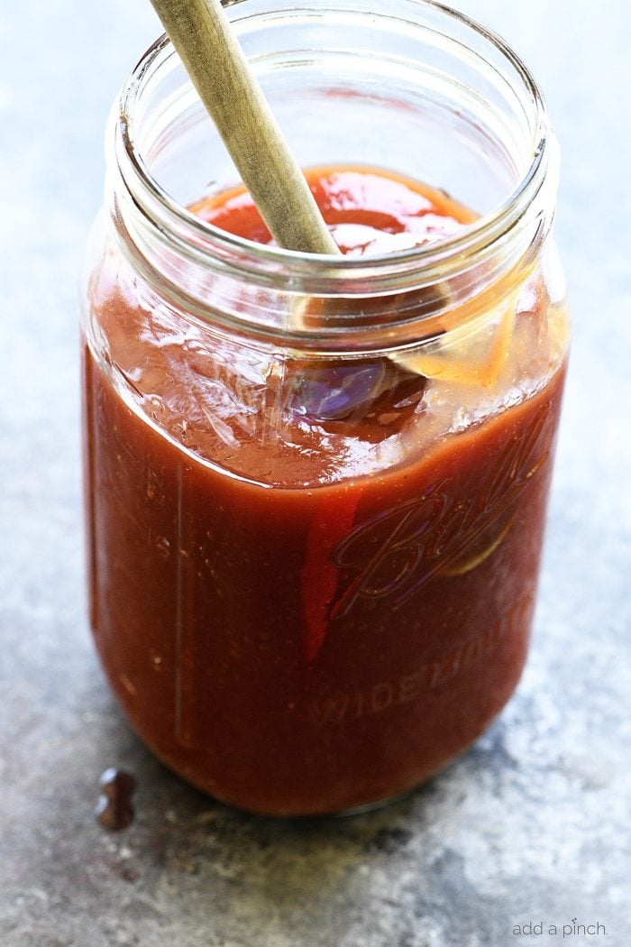 Homemade BBQ Sauce Recipe in a mason jar with a wooden spoon.