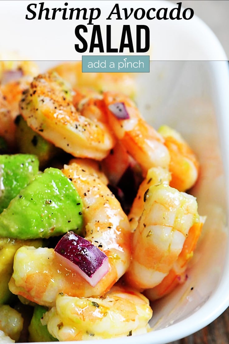 Shrimp Avocado Salad with bits of red onion, tossed in a zesty dressing, in a white bowl - with text - addapinch.com