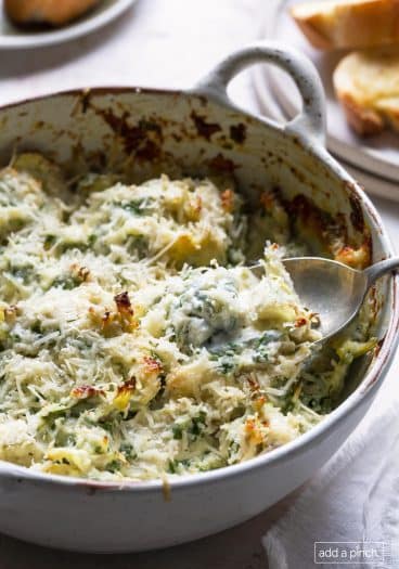 Photo of baked spinach artichoke dip in a white baking dish.