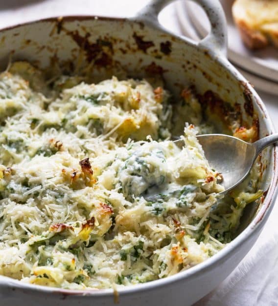 Photo of baked spinach artichoke dip in a white baking dish.