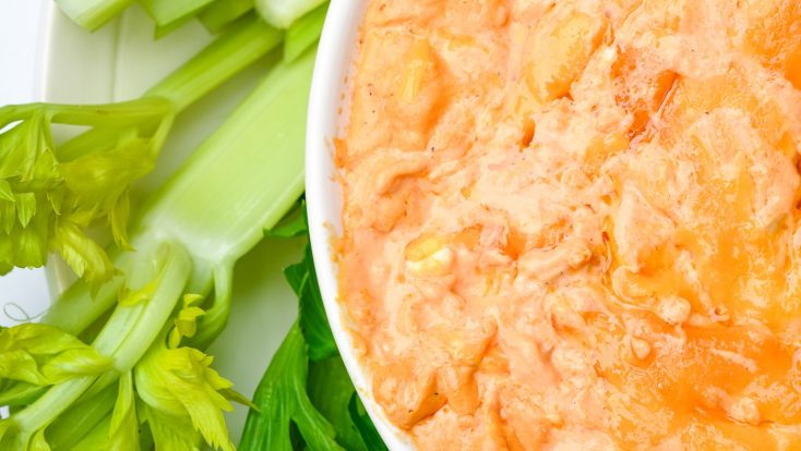 white bowl with buffalo chicken dip surrounded by celery on white background // addapinch.com