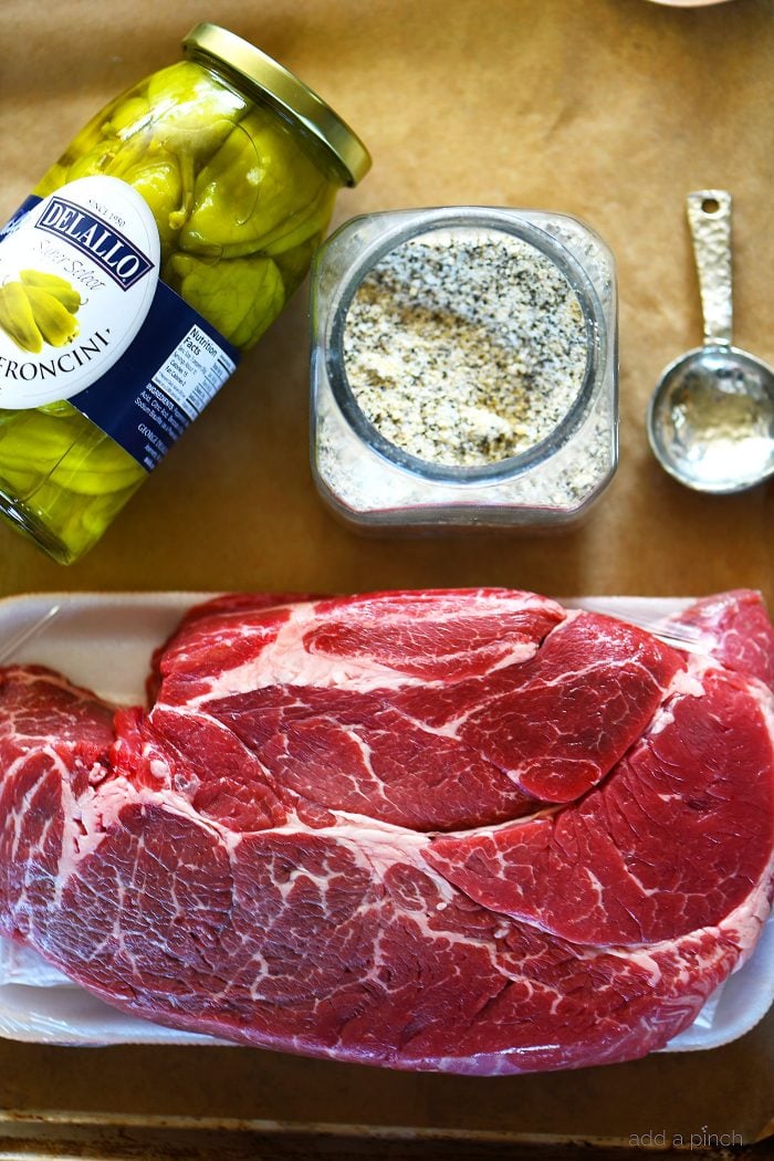 Ingredients for Mississippi Pot Roast - pepperoncini peppers, Stone House seasoning, chuck roast, on brown parchment paper.