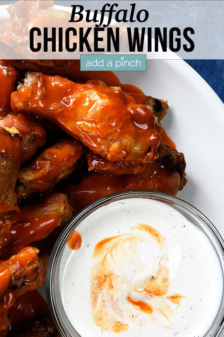 Buffalo Chicken Wings on a white plate with Ranch for dipping - with text - addapinch.com