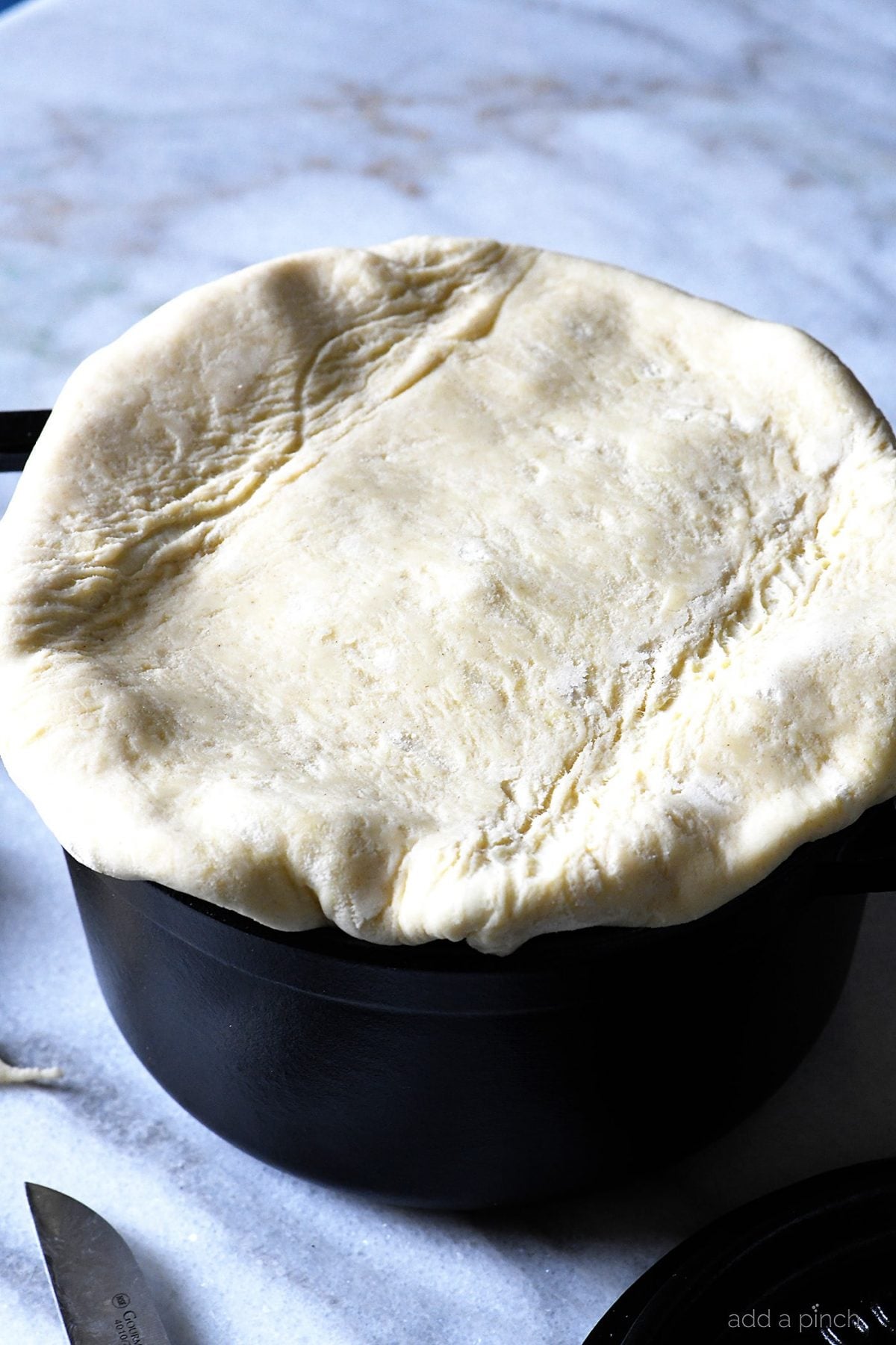 Puff pastry on top of chicken pot pie ready to be vented for cooking.