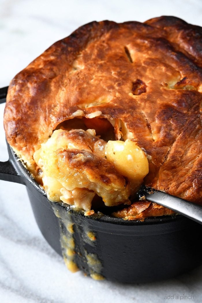 Spoonful of Chicken Pot Pie with puff pastry crust being dipped from dutch oven. // addapinch.com