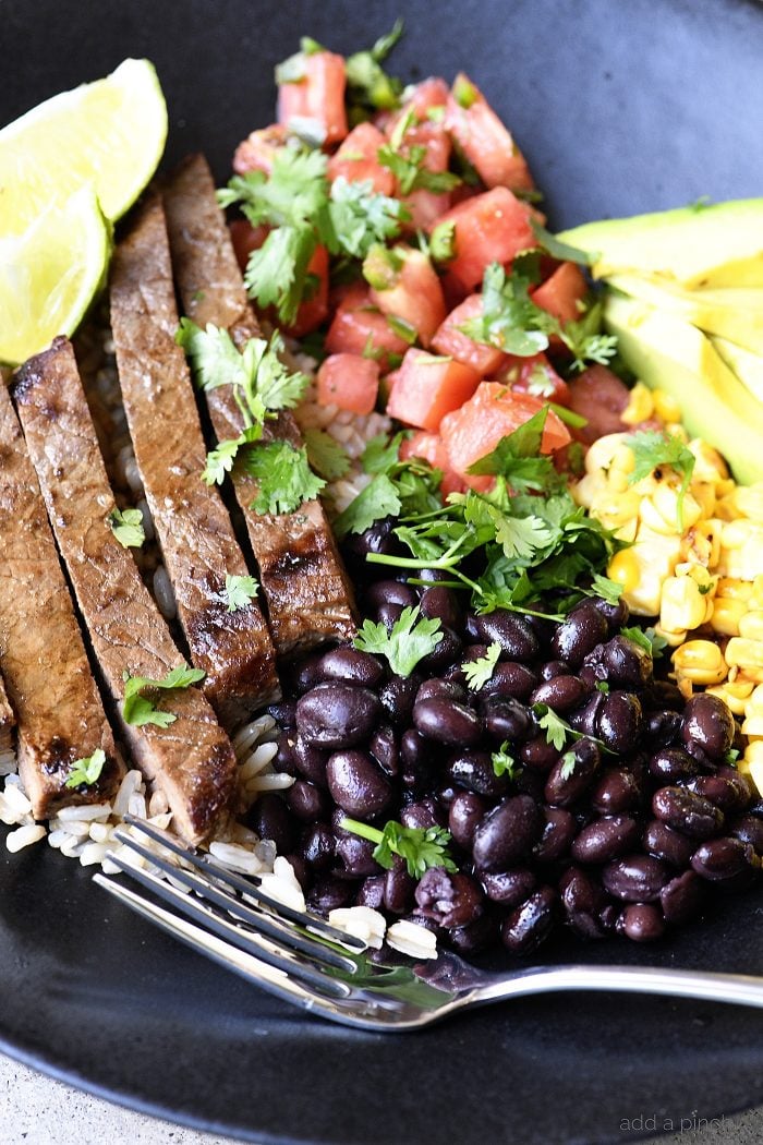 Steak strips, pico de gallo, corn, black beans, rice, lime, cilantro and avocado in a large serving bowl