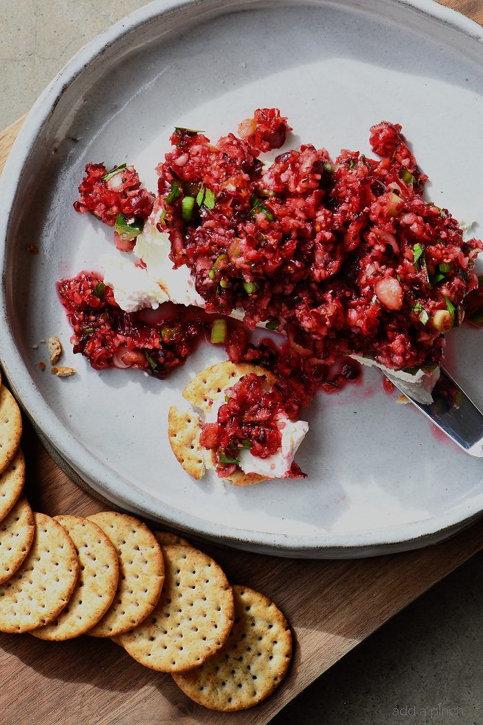 Cranberry Salsa Cream Cheese Spread Recipe - This quick and easy appetizer recipe made with a delicious fresh cranberry salsa over cream cheese and then is served with crackers, fruit, or chips. Makes a great make-ahead recipe for the holidays! // addapinch.com