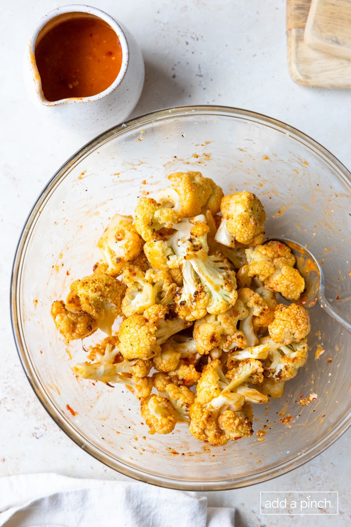 Cauliflower in a glass bowl tossed in buffalo sauce.