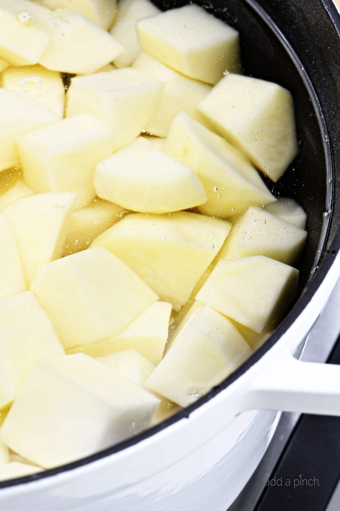Image of potatoes in a Dutch oven covered with water. // addapinch.com