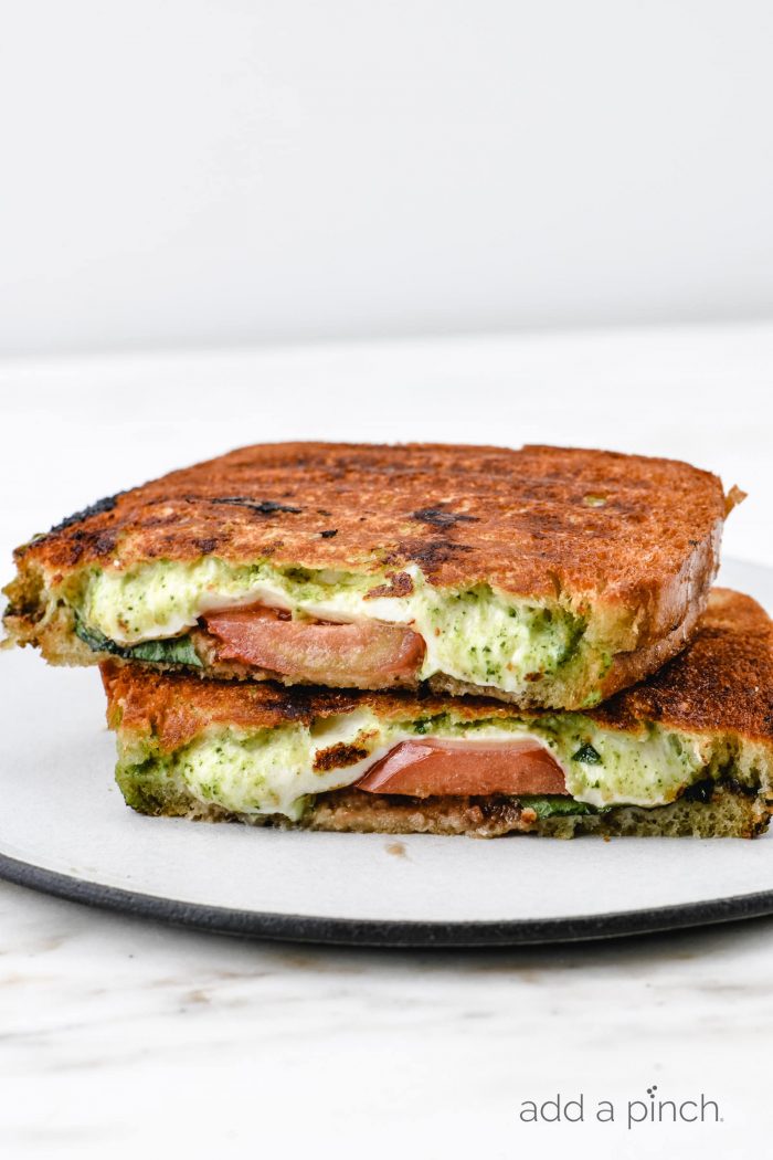 Caprese Grilled Cheese Sandwich is sliced in half on a white plate // addapinch.com