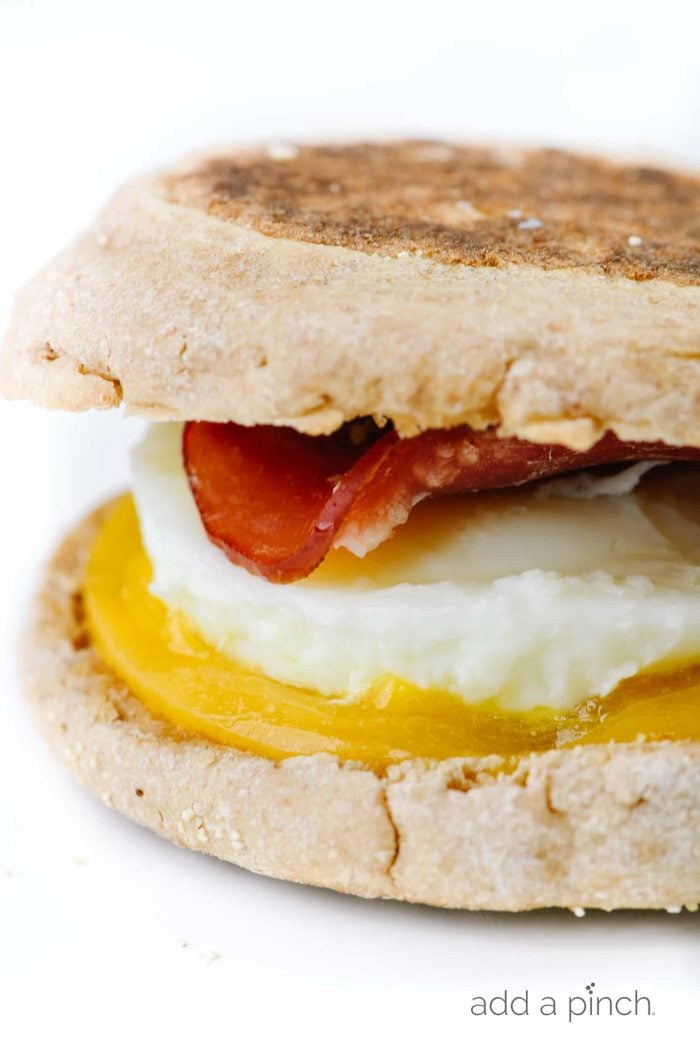 Side view of breakfast sandwich of English muffins, cheese, egg, and Canadian bacon // addapinch.com