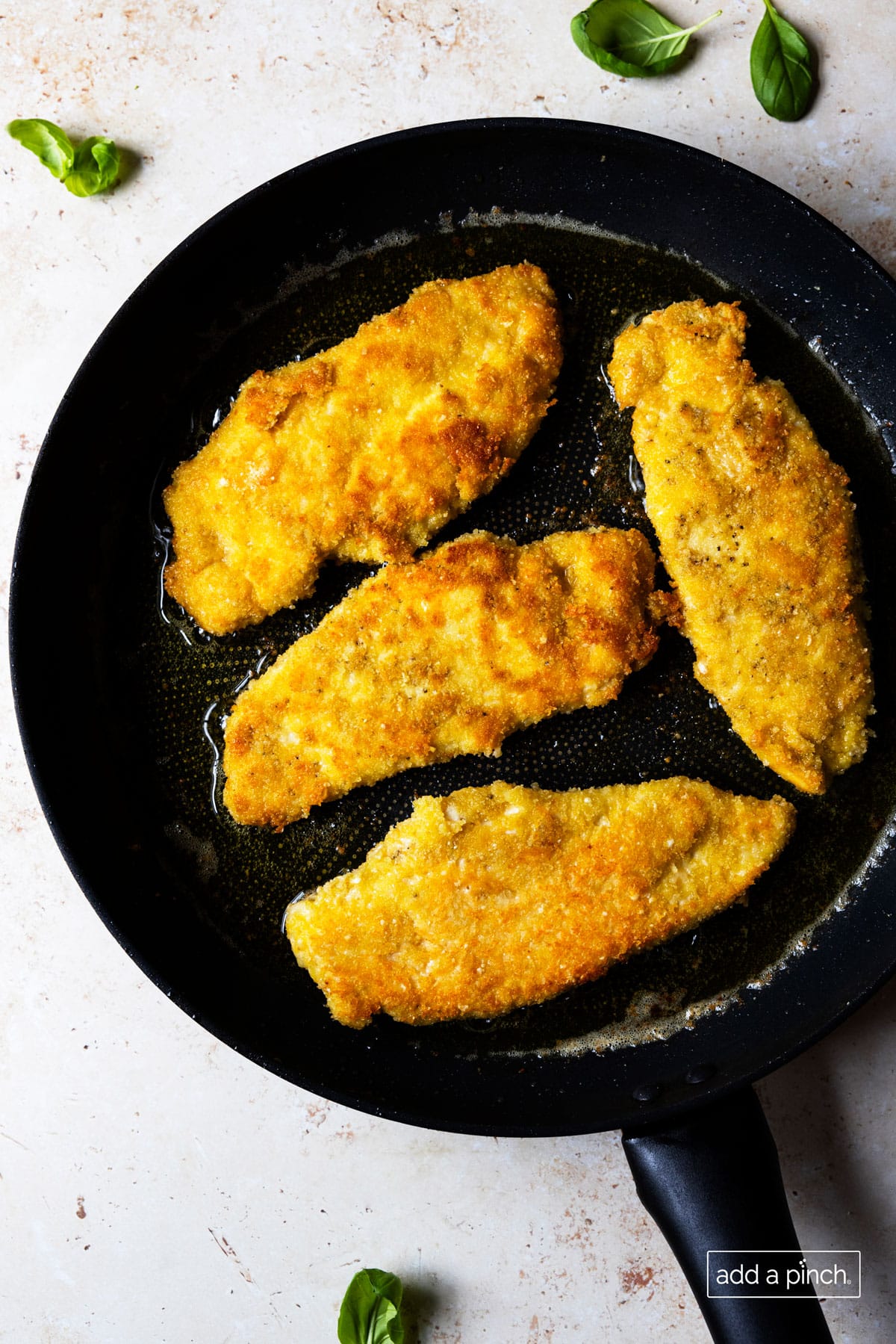 Photo of chicken cooking in a skillet until browned.