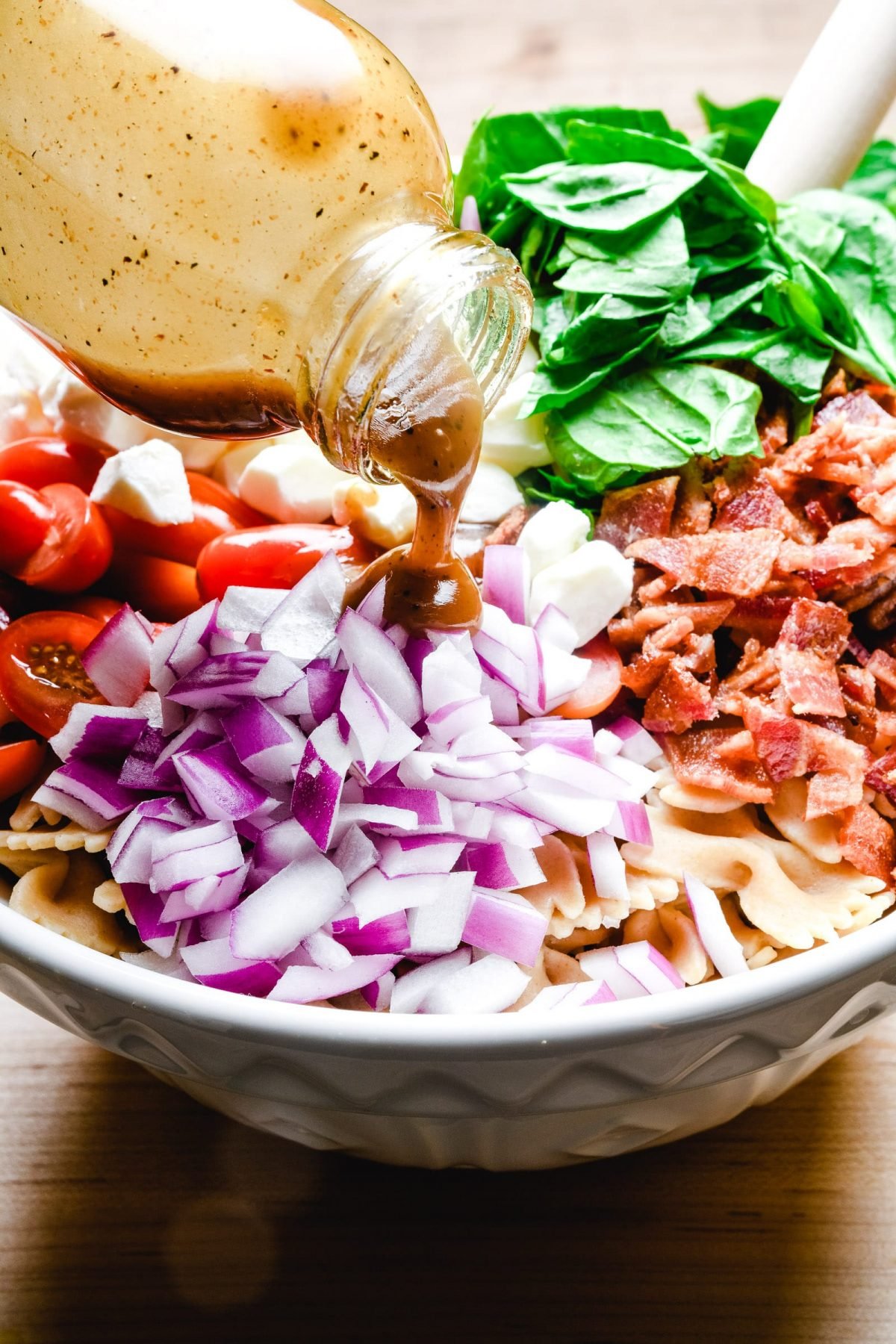 Dressing is poured over top of colorful pasta salad.