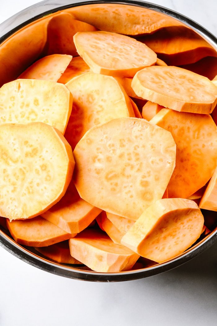 Slices of raw sweet potato in a stainless bowl // addapinch.com