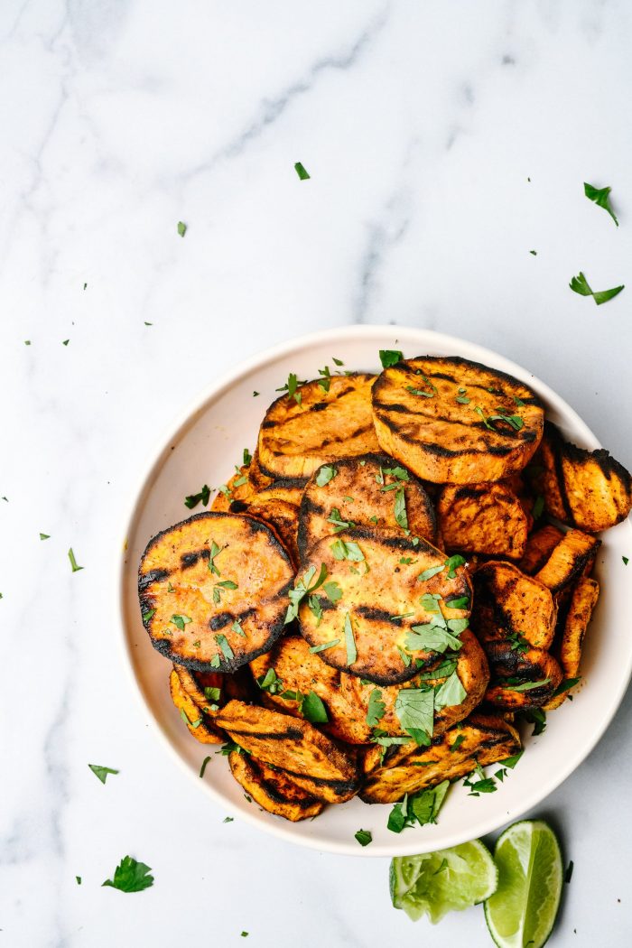 Spicy Grilled Sweet Potatoes with garnish on marble countertop // addapinch.com