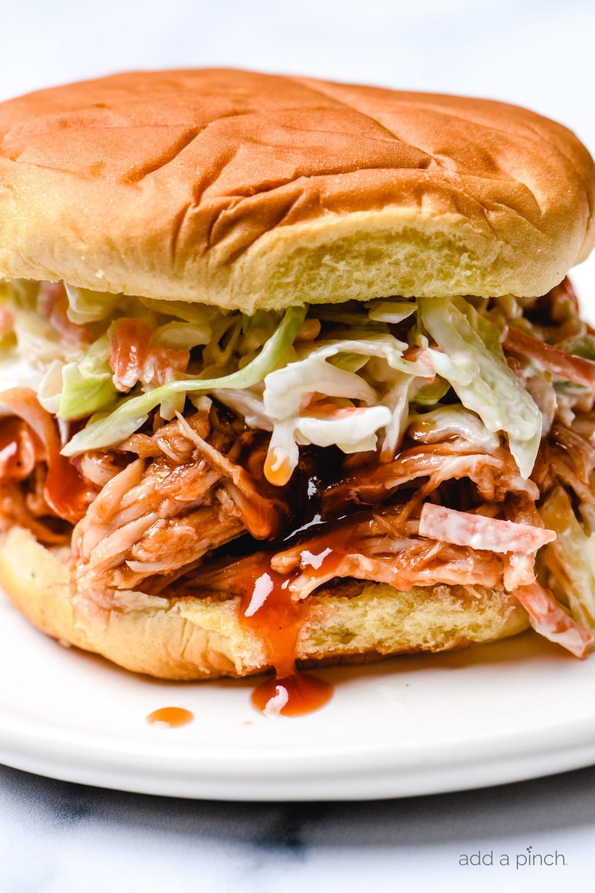 Close photo of BBQ Chicken Sandwich topped with coleslaw on a bun. 