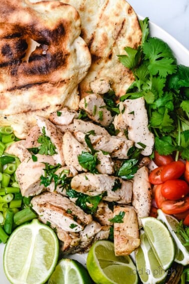Cilantro Lime Chicken surrounded by limes, cilantro, tomatoes and a grilled tortilla // addapinch.com