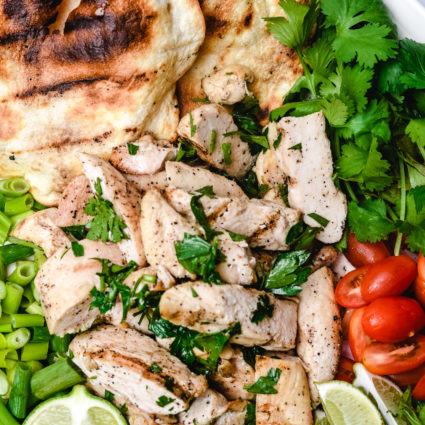 Cilantro Lime Chicken surrounded by limes, cilantro, tomatoes and a grilled tortilla // addapinch.com