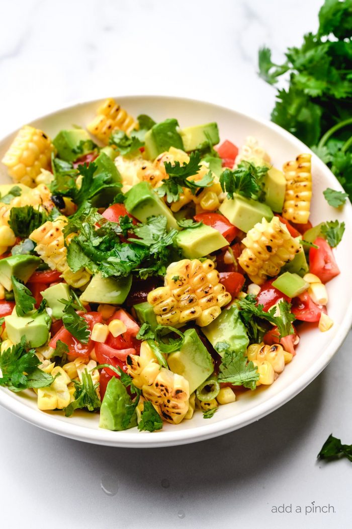 Grilled corn saladÂ features fresh summer corn, avocado, tomato, jalapeno, and onion. A quick, easy and healthy recipe that is perfect for summer barbecues! // addapinch.com